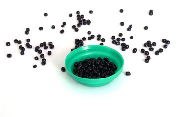 Fototapeta na wymiar Black beads. Isolate Beads. Sprinkled beads. Beads in a green cap. Material for creativity