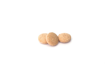 Three round light brown pills on a white background. Three pills isolated
