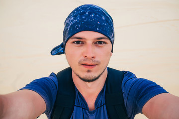 male Caucasian tourist wearing a bandana makes a selfie at camera