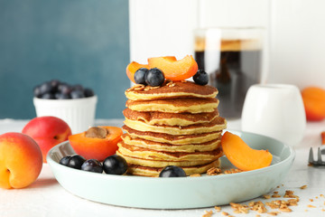 Composition with pancakes and fruits on white table. Sweet breakfast