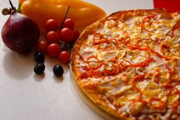 Hot italian pizza on a table with vegetables