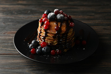 Plate with pancakes and berries on wooden background. Sweet breakfast