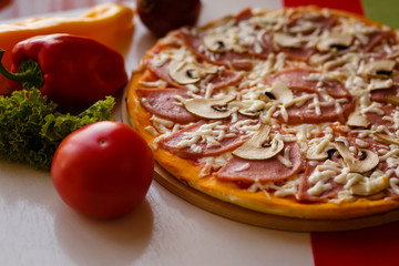 Hot italian pizza on a table with vegetables