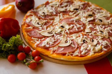 Hot italian pizza on a table with vegetables