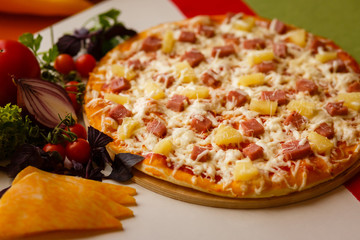 Hot italian pizza on a table with vegetables