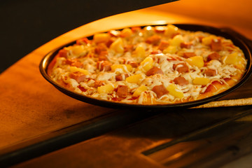 Baking a pizza in oven. Hot pizza in a dish on a shovel in a furnace.