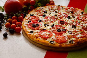 Hot italian pizza on a table with vegetables