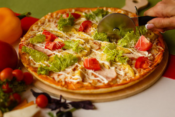 Cutting a baked pizza on slices. Close-up cutter knife.