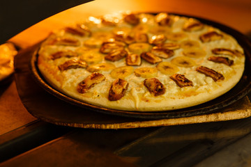 Baking a pizza in oven. Hot pizza in a dish on a shovel in a furnace.