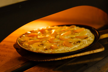 Baking a pizza in oven. Hot pizza in a dish on a shovel in a furnace.