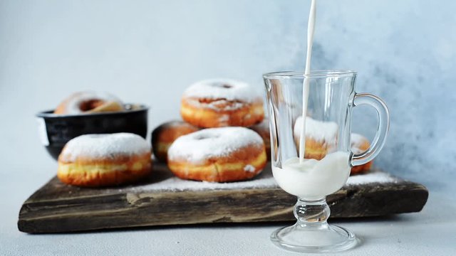 Pouring milk into a glass on a light background. Delicious Homemade Donuts