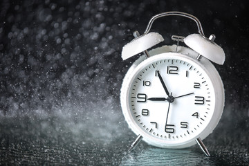 white retro alarm clock in a black background under the water drops.. Morning. Break. Motivation....