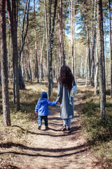 Little boy walks in a spring forest with mother
