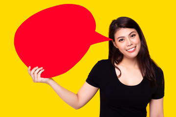 Young Asia woman holding red speech bubble on yellow background. Asian female show sign speech bubble banner, pretty girl get happy, smile face. Beautiful joyful lady thinking idea, telling someone