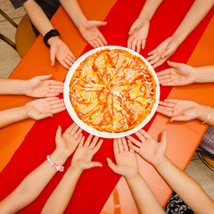 Kids hands sharing a pizza taking a slices