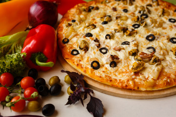 Hot italian pizza on a table with vegetables