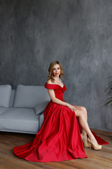 Fototapeta na wymiar girl in a red dress sitting on the floor near the mirror