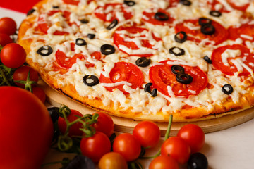 Hot italian pizza on a table with vegetables