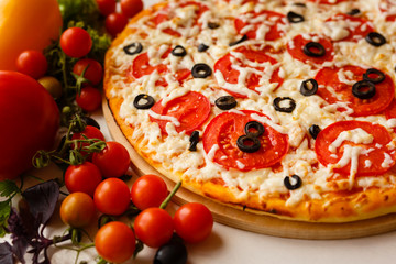 Hot italian pizza on a table with vegetables