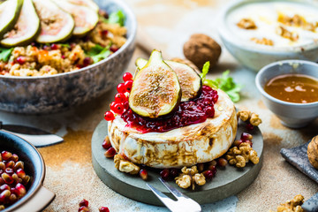 close-up view of tasty healthy dish with fruits, nuts, honey, camembert cheese, couscous and pomegranate seeds on wooden table