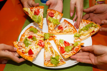 Kids hands sharing a pizza taking a slices