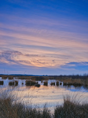 Colorful sky and colorful water in lake reflected in evening, focus on grass in foreground