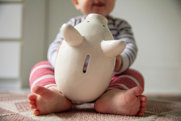 Family finance concept. Young baby playing with a piggy bank money box