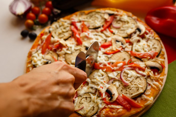 Cutting a pizza to a slices by cutter. Close-up photo