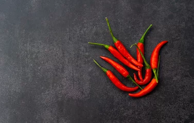 Fotobehang rode hete chili pepers op zwarte muur achtergrond © Lemau Studio