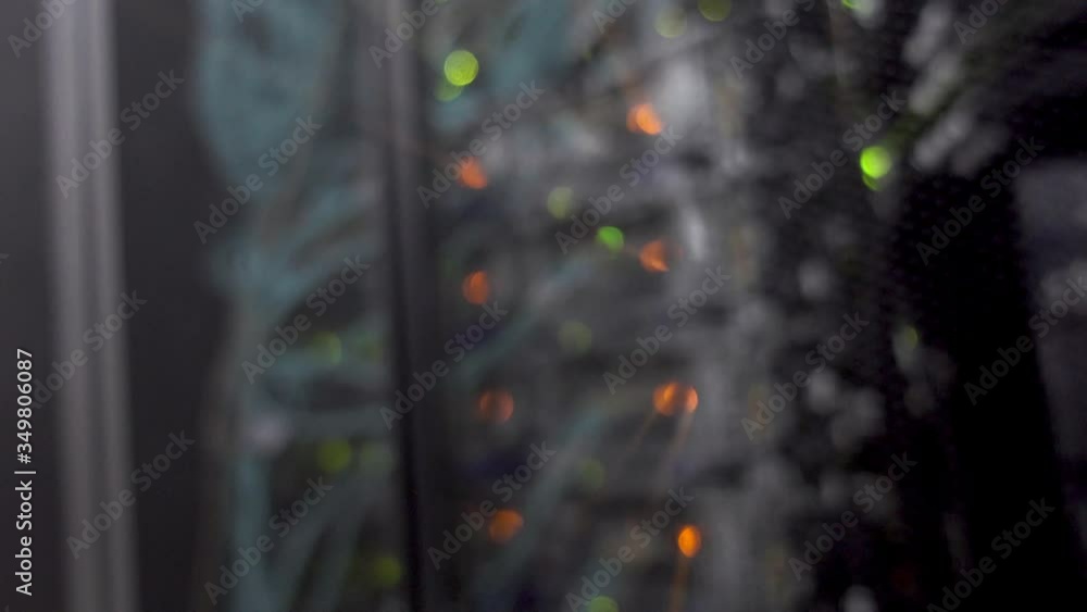 Poster green orange bokeh led lights blinking on back side of working data server. video contains vibration