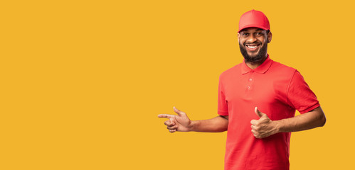 Black Courier Man Pointing Fingers Aside Gesturing Thumbs-Up, Yellow Background