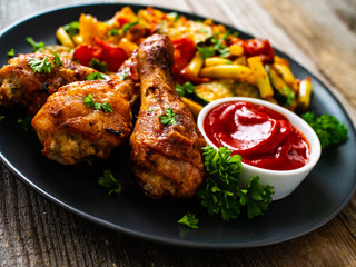 Barbecue chicken drumsticks with vegetables on wooden table
