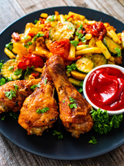Barbecue chicken drumsticks with vegetables on wooden table
