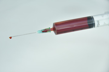 Syringe and needle filled with blood.