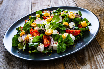 Fresh greek salad - feta cheese, cherry tomatoes, lettuce and onion wooden table
