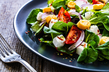 Fresh greek salad - feta cheese, cherry tomatoes, lettuce and onion wooden table
