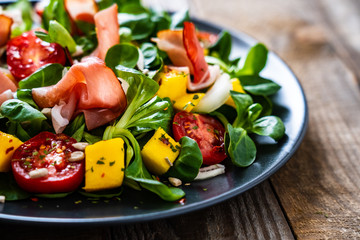 Tasty salad - ham and vegetables on wooden background