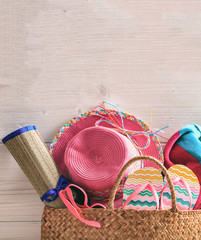 Summer vacation concept on pink background. Straw hat, flip flops, sunglasses and towel