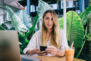 Focused female browsing smartphone in resort cafe