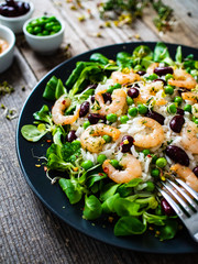 Prawns with rice and vegetables on wooden table