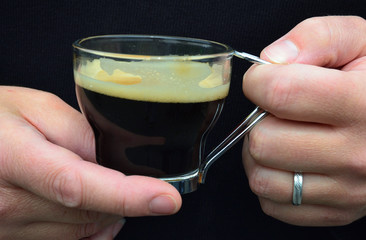 Personne tenant un expresso dans une tasse transparente