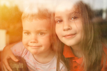kids siblings boy and girl looks through the window during covid-19 quarantine. stay at home, let's all be well. flare