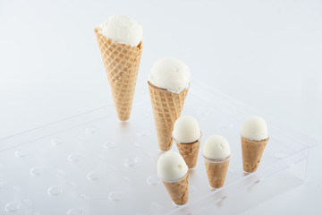 set of handmade organic vanilla ice cream in different sizes in waffle cones on a stand - 349813810