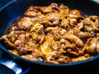 Chicken nuggets frying in pan with red onion