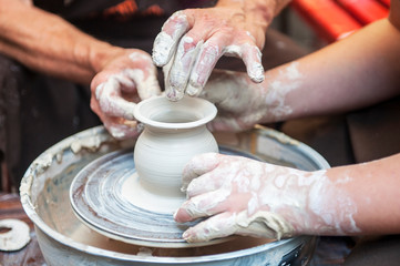 The potter makes pottery dishes on potter's wheel.