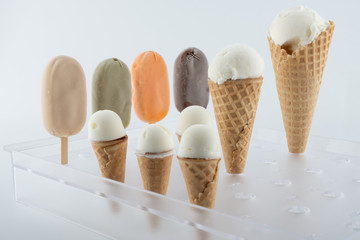 set of organic handmade ice cream of different flavors on sticks and waffle cones with vanilla, chocolate, pistachio, mango flavors close-up on the stand