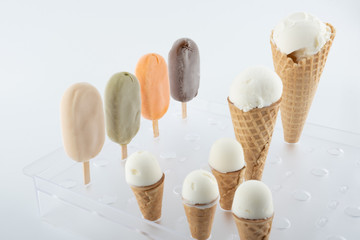 set of organic handmade ice cream of different flavors on sticks and waffle cones with vanilla, chocolate, pistachio, mango flavors close-up on the stand