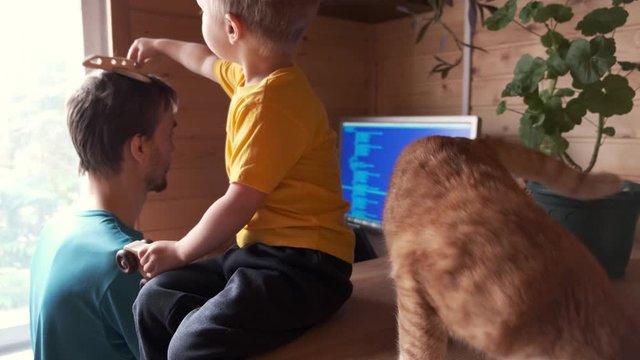 parenthood multitasking, father freelancer working from home, small child with cat sits and plays near, side view, concept of self-isolated lifestyle workplace and stay home in pandemic quarantine 