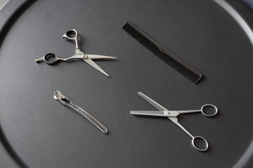 hairdresser tool scissors and comb on a black background, place for an inscription