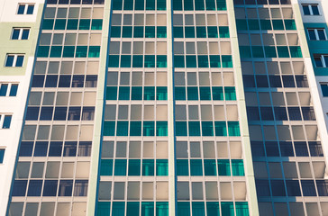 Close-up - part of new multistorey panel home with balconies and windows, new building in sunlight.